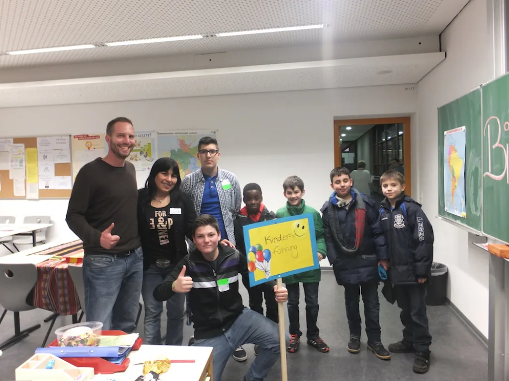 Gruppe posiert vor der Tafel, ein Kind hält ein Schild.
